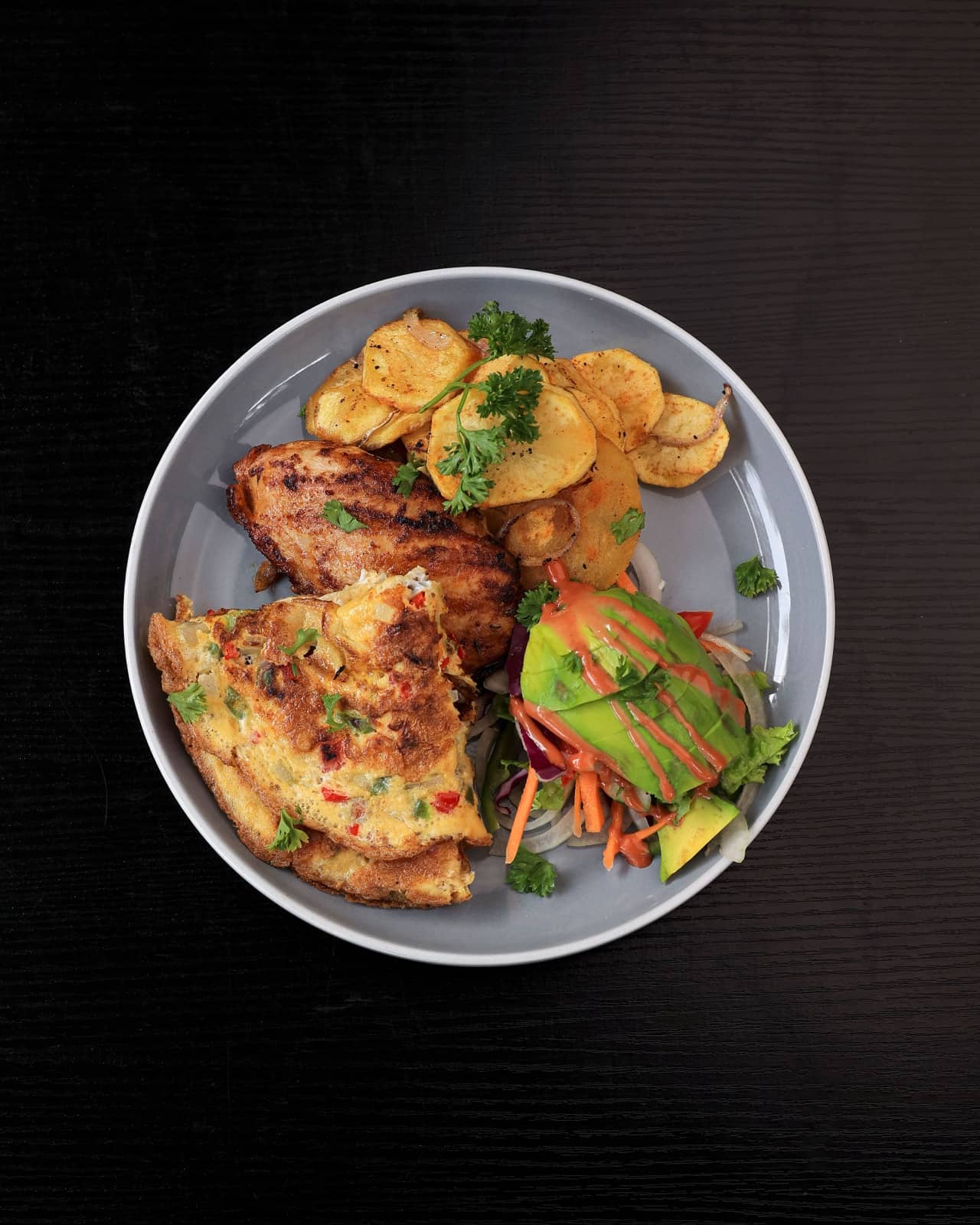 Chef's breakfast plate from above: chicken, eggs, potatoes, avocado salad