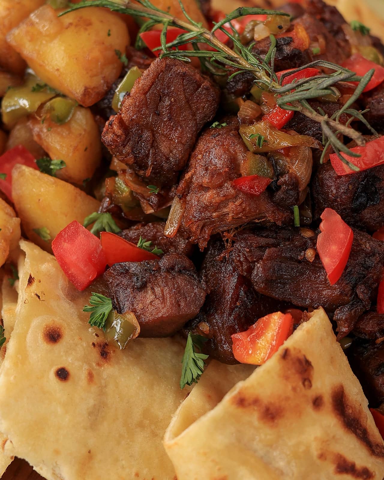 Slow-cooked goat with potatoes, peppers and rosemary