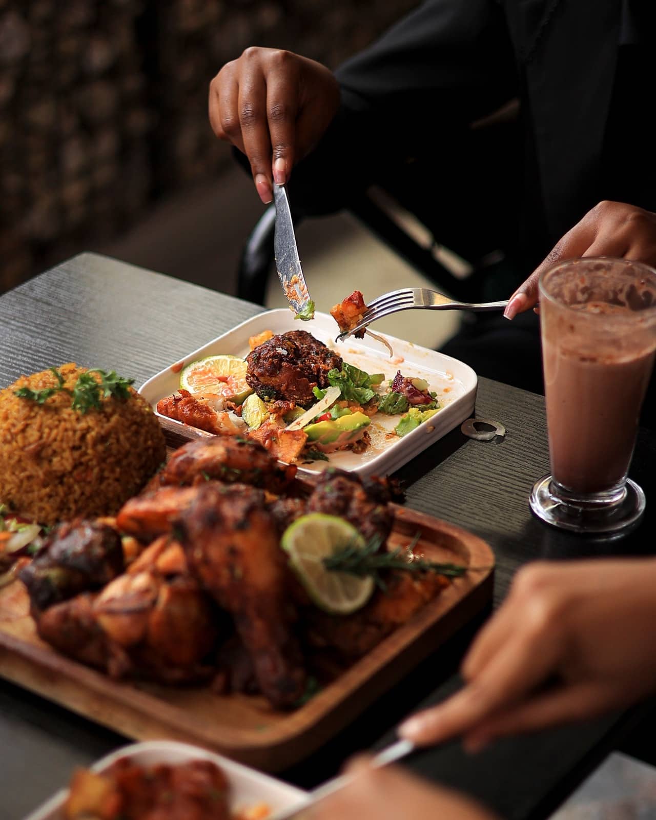 Guests cutting into grilled chicken, milkshakes on the table
