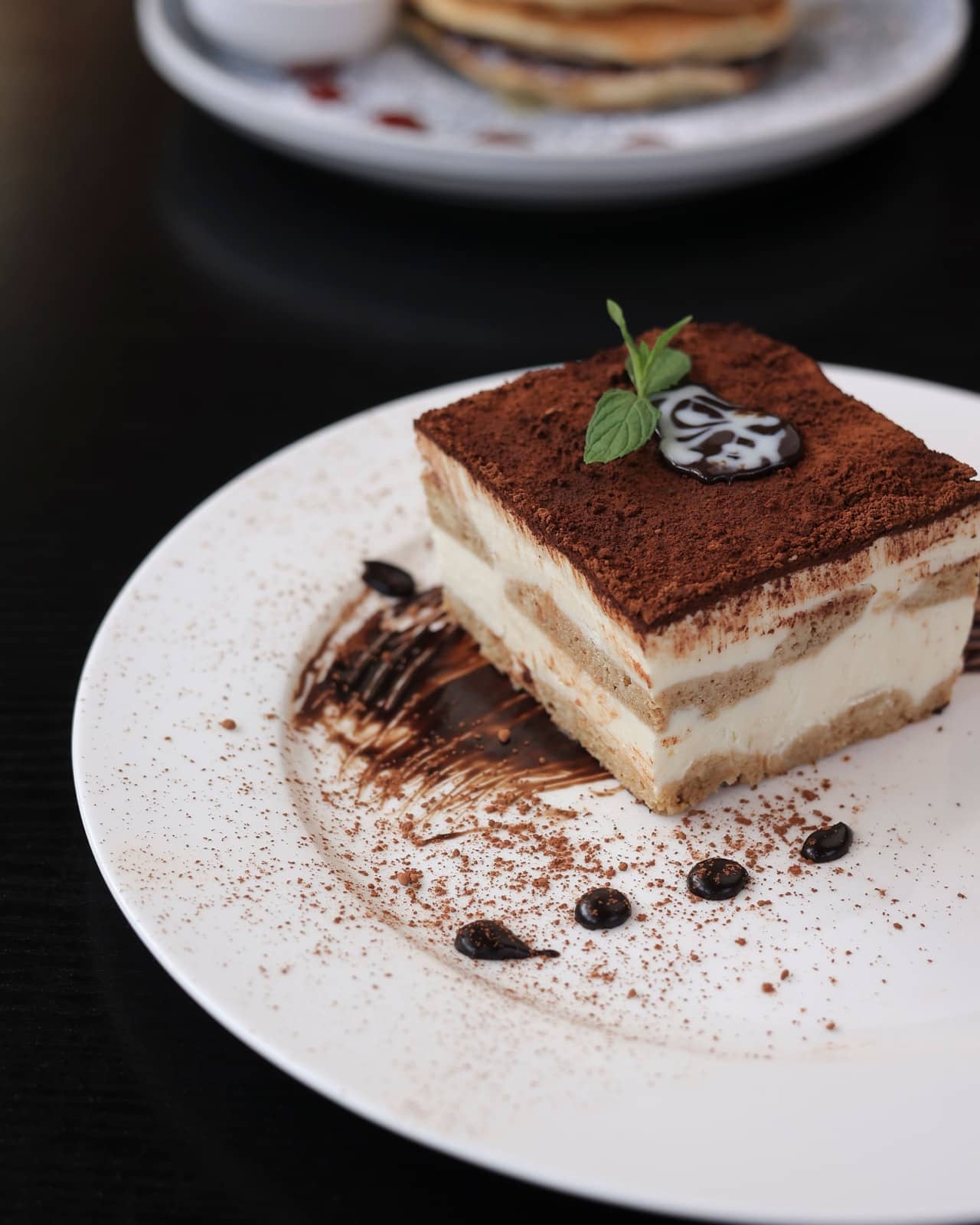 Tiramisu with pancakes in the background
